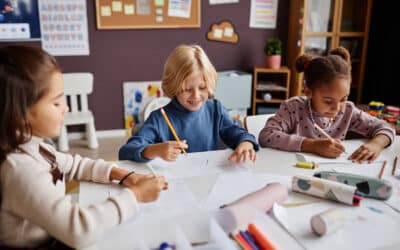 Several diligent learners of nursery school drawing with crayons